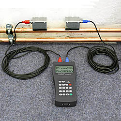 The PCE-TDS 100H ultrasonic flow meter measuring a pipe.