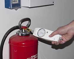 An analogue force sensor taking measurement on a fire extinguisher.
