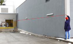 The PCE-LDM 50 laser distance meter measuring a wall distance